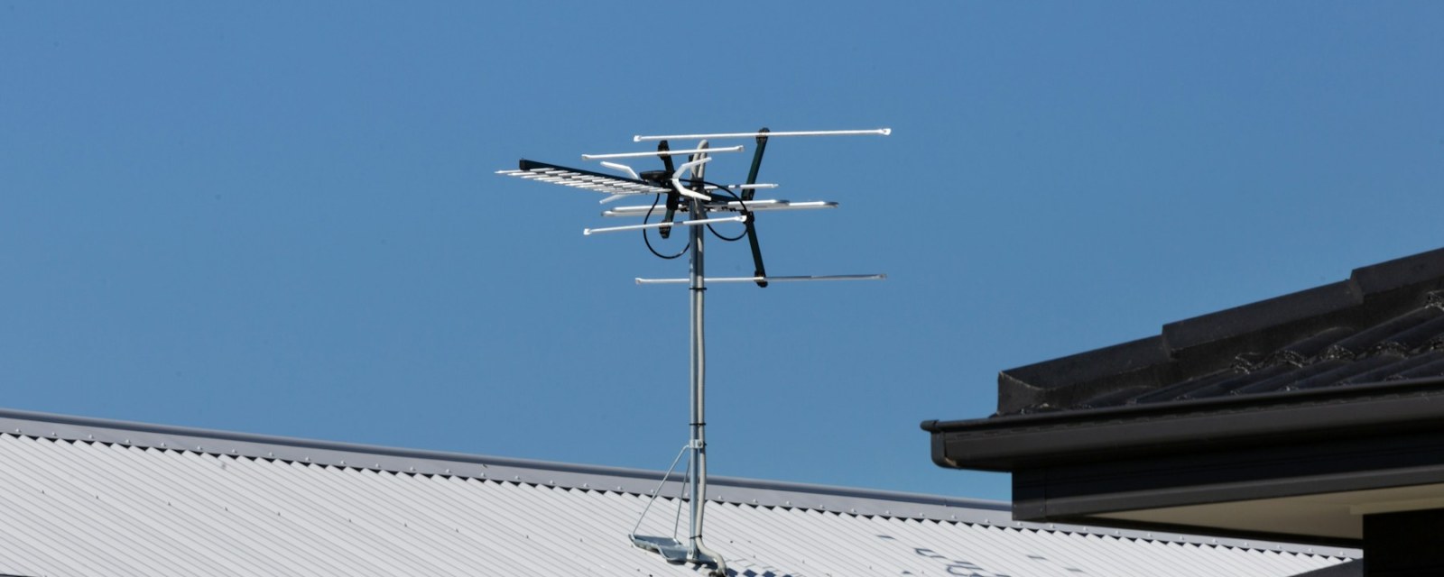 A directional TV antenna on a roof mast, aimed toward distant transmitters