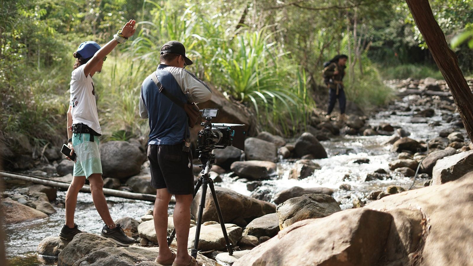 A documentary film crew shooting on location beside a forest stream